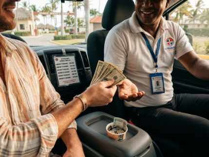 Tourist handing US dollar bills to a taxi driver in Punta Cana