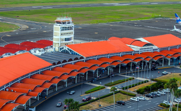Aerial view of Cibao International Airport (STI) terminal with its distinctive orange arched roof and control tower.
