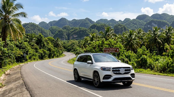 A white luxury SUV driving on a lush tropical road with a sign for Parque Nacional Los Haitises and karst mountains in the background.