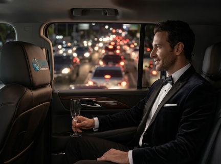 Man in tuxedo in luxury car with nighttime city traffic view.