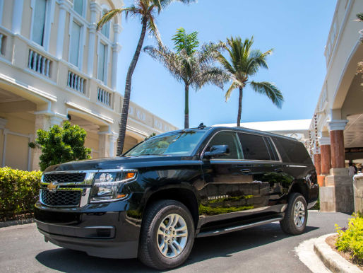 Black Chevrolet Suburban parked outside a luxury resort with palm trees