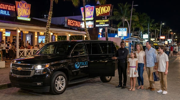 A black taxi SUV at night outside a CoCo Bongo club, with a driver opening the door for a family of four.