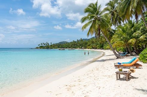 Hermosa playa tropical de arena blanca y aguas turquesas con palmeras