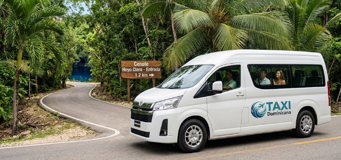 Furgoneta de Taxi Dominicana brindando servicio de transporte hacia la entrada del Cenote Hoyo Claro rodeada de naturaleza tropical