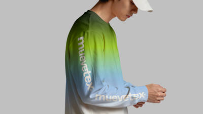 A model wearing a long-sleeve shirt with a green-to-blue gradient sleeve printed with the Muevetex wordmark, shown from the side against a grey background.