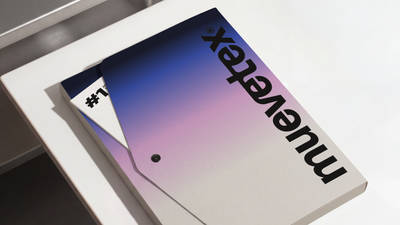 The Muevetex brand guidelines folder in a navy-to-pink gradient, shown upside down on a desk with its "#1" insert peeking out.