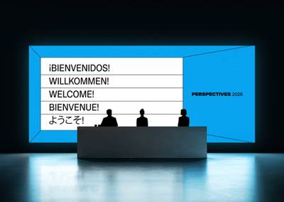 Main auditorium stage screen with a large blue 3D perspective frame layout and panel speakers at the desk.
