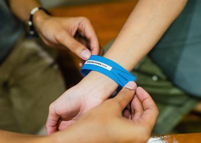 Close-up of an attendee wearing a cyan blue All Access wristband with modern typography.