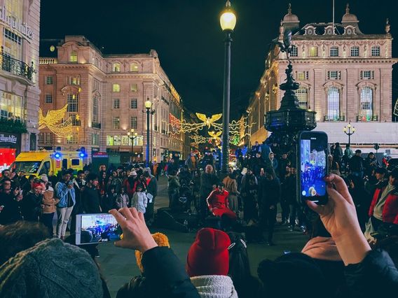 People taking pictures of a street performer. 