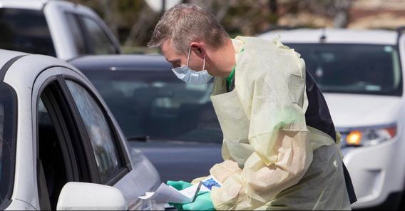 Cullen Anderson, RN, screens people in a line of cars waiting to be tested for coronavirus COVID-19 at a drive-thru testing station in Idaho