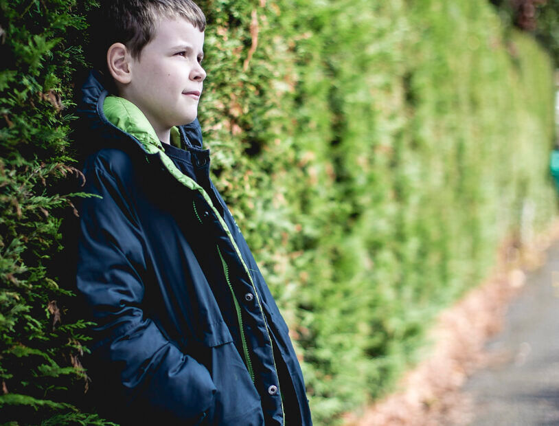 Child Boy Leaning Against a Bush