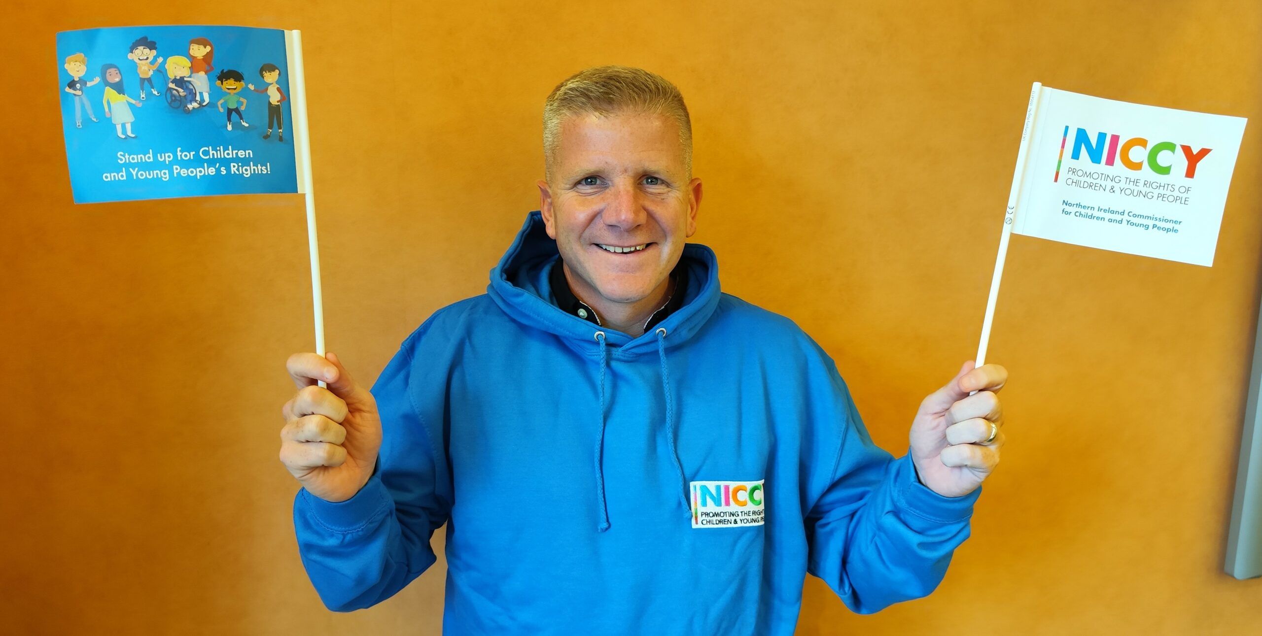 Chris Quinn, NI Children's Commissioner, holding NICCY flags