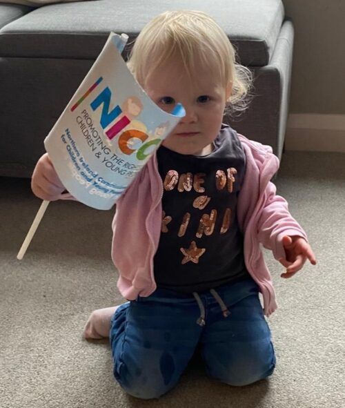 This is a photo of a baby waving a NICCY flag