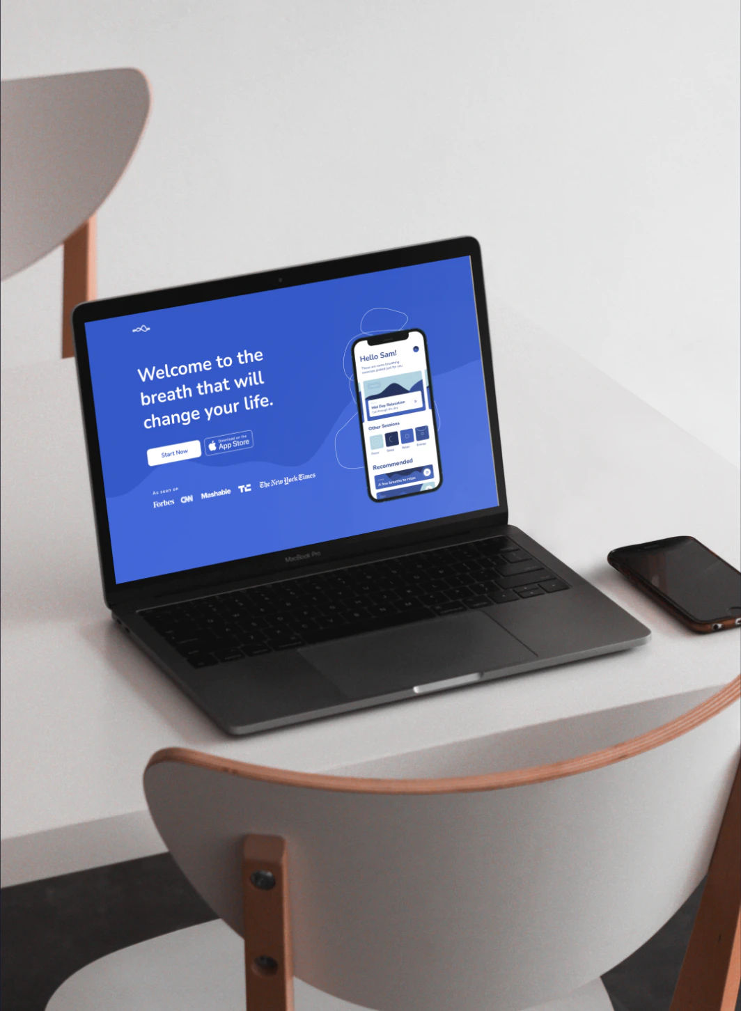 macbook showing breathology website in full screen over a white desk and chairs