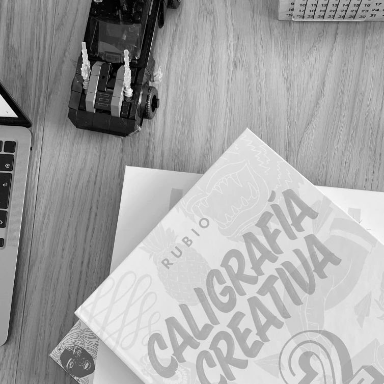 books on a table displaying the title creative typography, a computer and a lego set in a black & white photo
