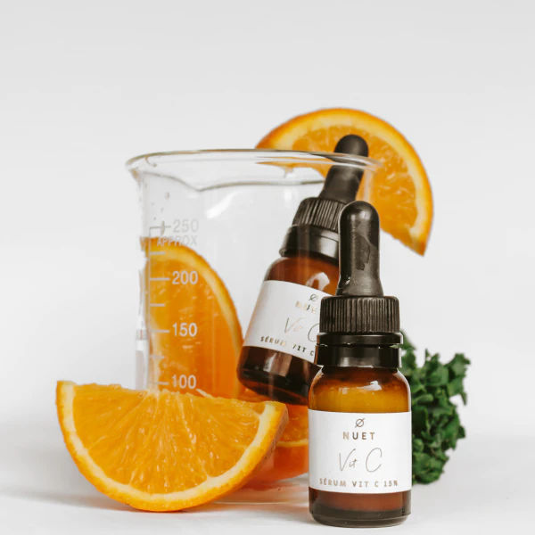 dropper bottles of skin vegan serum with vitamine c among slices of orange