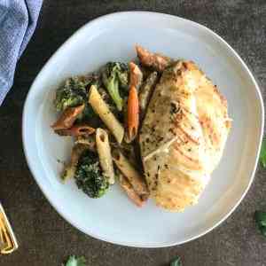 chicken breast on a plate with with penne pasta and broccoli