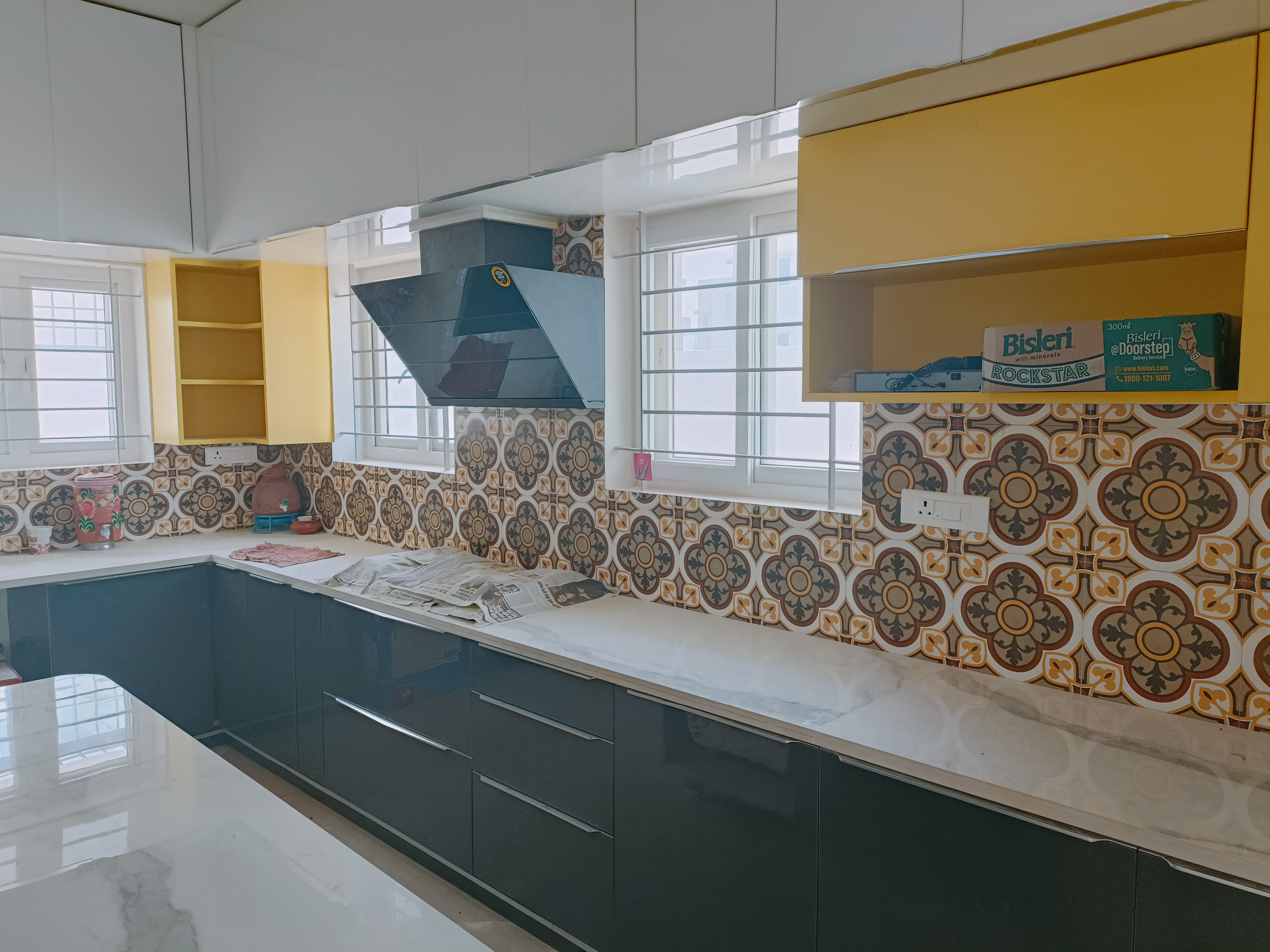 Modern L-Shaped Modular Kitchen with Gray & Yellow Cabinets and Stylish Wall Tiles