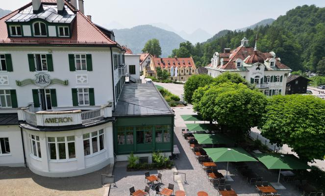 Gebäude im Grünen mit Terrasse und zwei großen grünen Sonnenschirmen