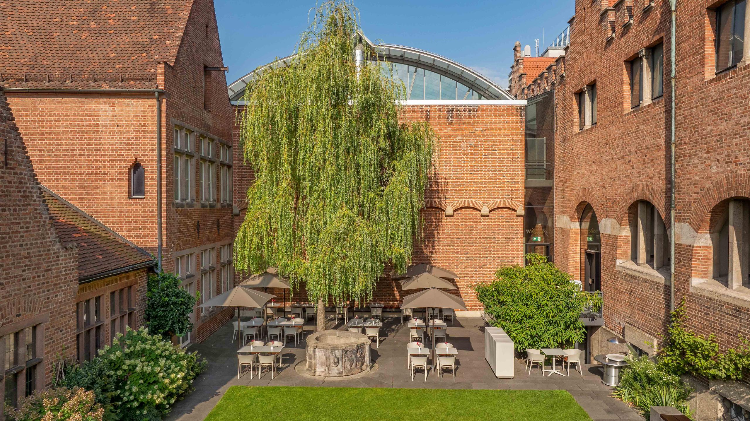 Backsteinhaus mit einer Terrasse und braunen Sonnenschirmen