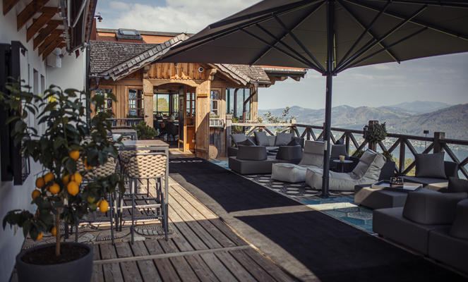 Holzhaus mit einer Terrasse und grauen Sonnenschirmen