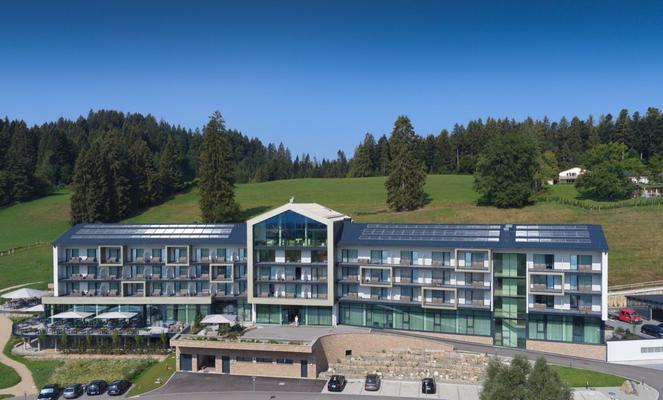 Eine Terrasse mit Tischen unter einem großen Sonnenschirm inmitten einer grünen Landschaft
