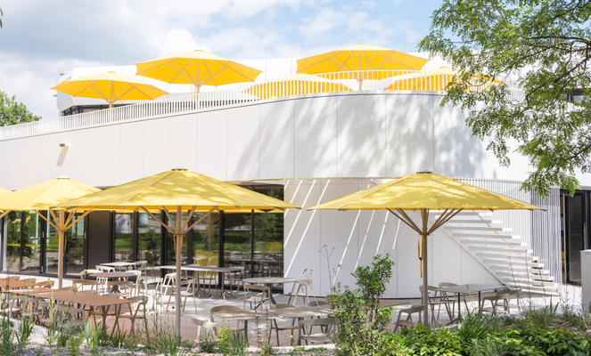 Moderne Terrasse mit gelben Sonnenschirmen neben einem Bürogebäude.