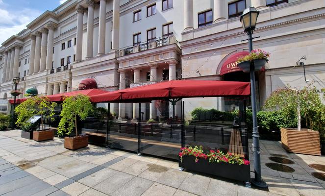 Historisches Gebäude mit Terrasse und roten Sonnenschirmen.