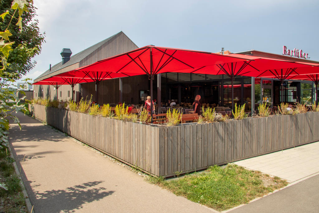 Restaurant von Außen mit vier roten Sonnenschirmen auf der Terrasse