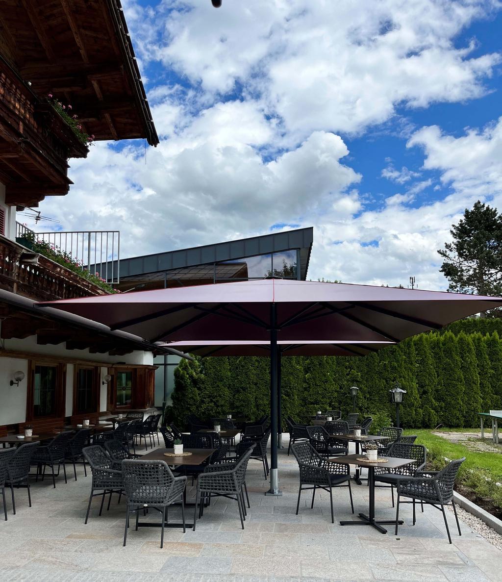 Bruggerhof, Kitzbühel in Österreich mit roten ALBATROS Schirmen Beschattete Terrasse mit roten Sonnenschirmen