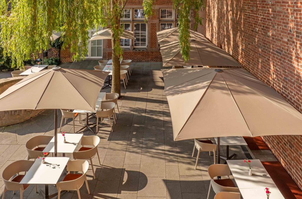 Café Arte mit braunen FILIUS Schirmen Backsteinhaus mit einer Terrasse und braunen Sonnenschirmen
