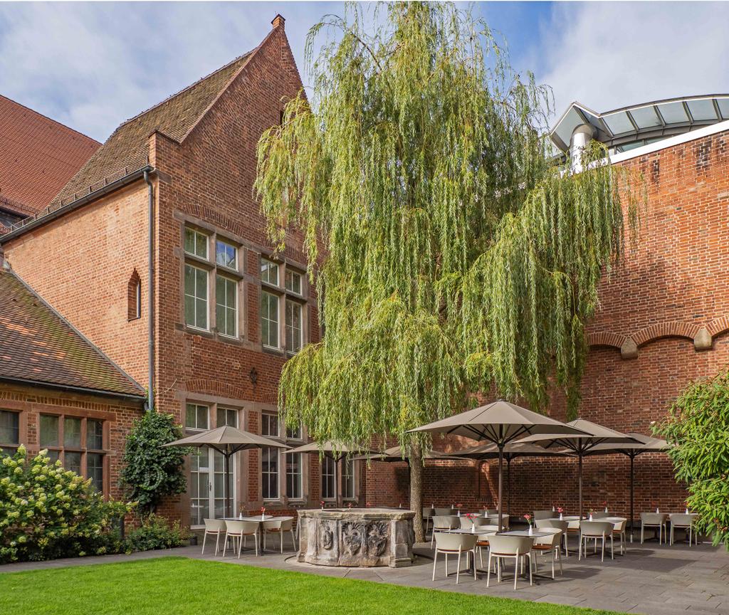 Café Arte mit braunen FILIUS Schirmen Backsteinhaus mit einer Terrasse und braunen Sonnenschirmen