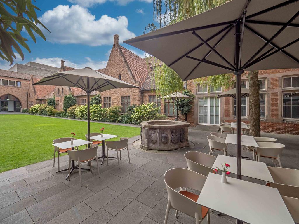 Café Arte mit braunen FILIUS Schirmen Backsteinhaus mit einer Terrasse und braunen Sonnenschirmen