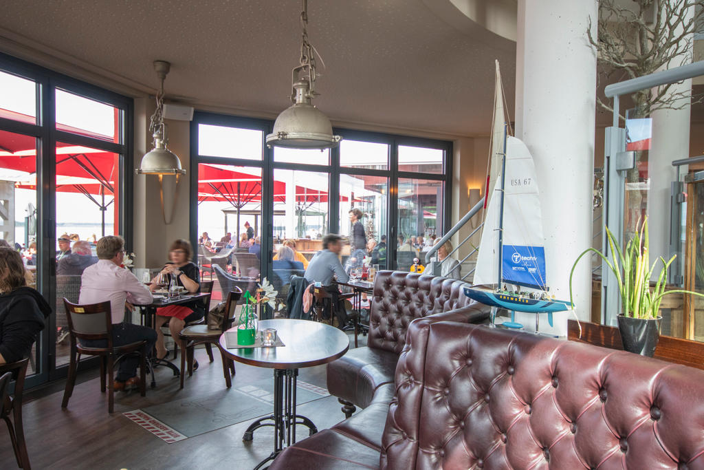 Restaurant von innen mit Aussicht auf rote Sonnenschirme