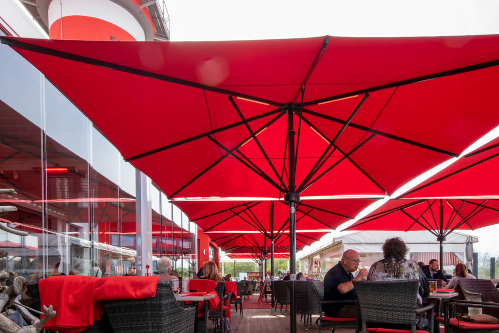 Der LeuchtTurm Elsterheide mit roten SCHATTELLO Schirmen Terrasse mit roten Sonnenschirmen
