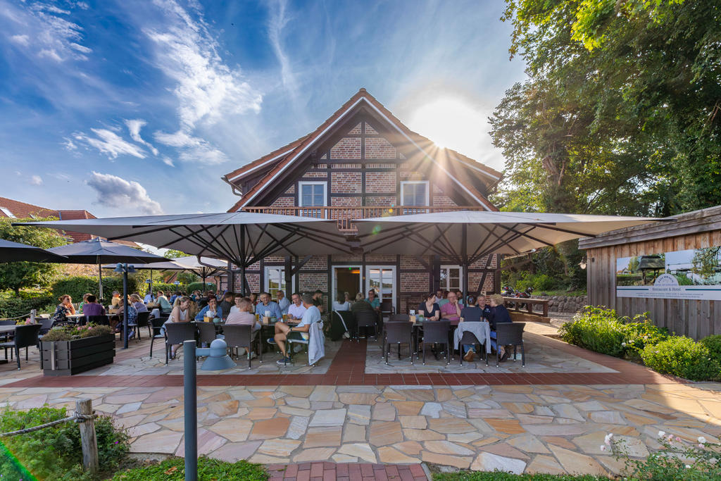 Ein Gebäudekomplex am See mit Innenhof und weißen Sonnenschirmen