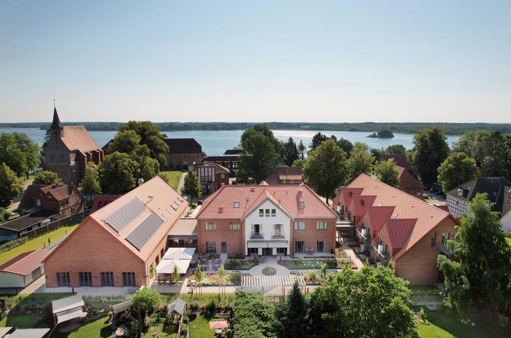 Ein Gebäudekomplex am See mit Innenhof und weißen Sonnenschirmen