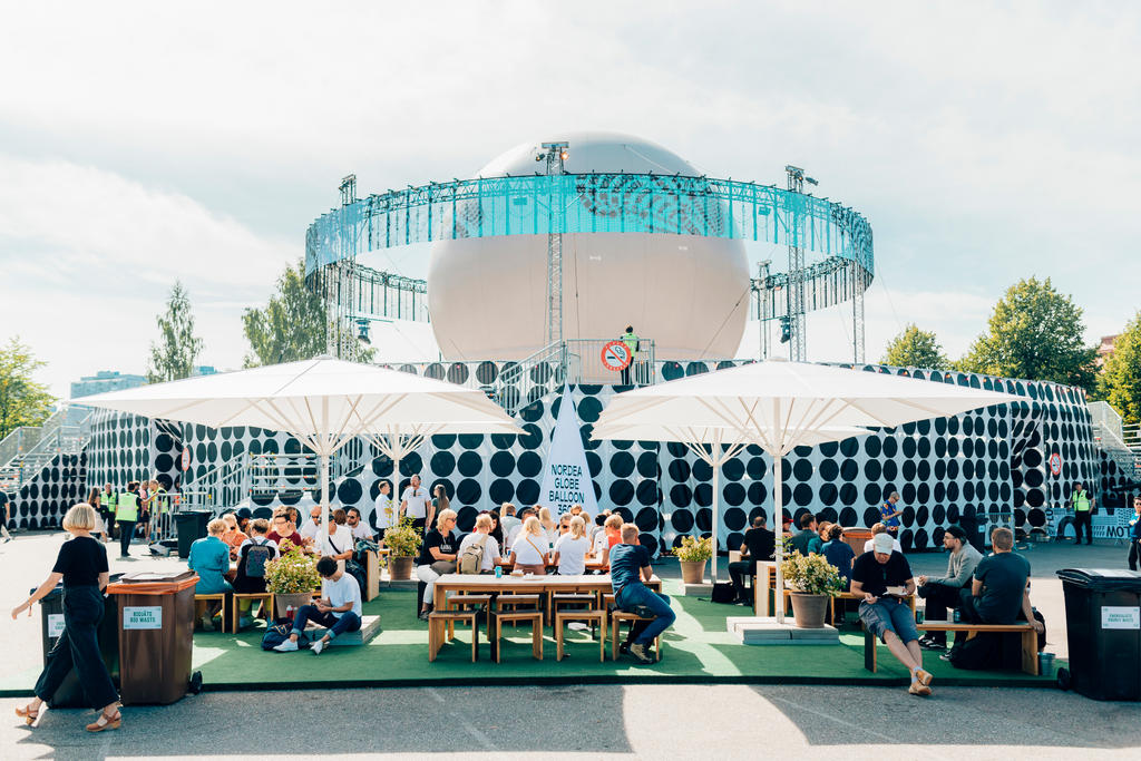 Flow Festival with white SCHATTELLO parasols Flow Festival with outdoor seating area and white parasols.