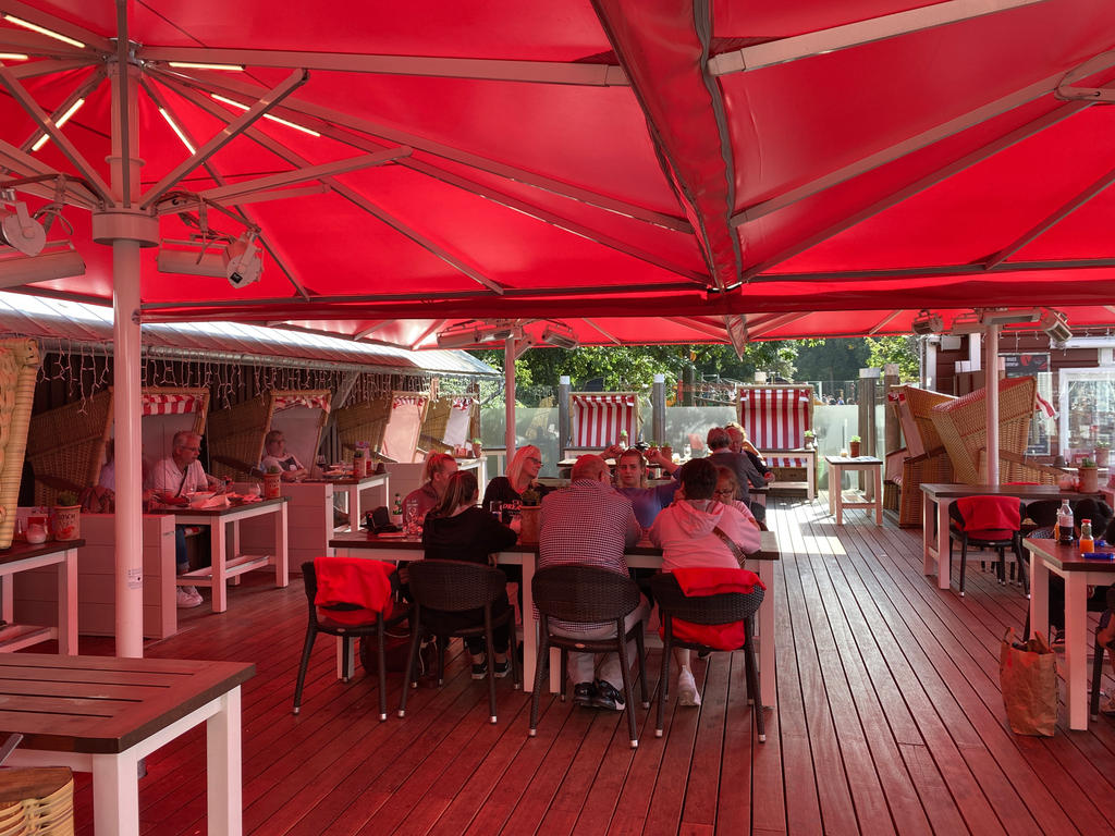 Terrasse am Meer mit roten Sonnenschirmen