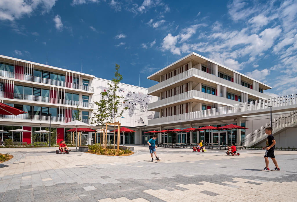 Grundschule Ravensburger Ring Muenchen Deutschland Aussen 1 Schule mit spielenden Kindern und roten Sonnenschirmen