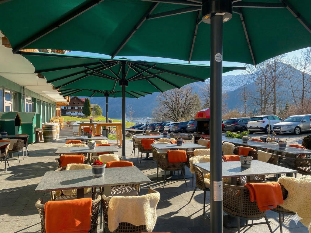 Hôtel avec des Parasols verts et une terrasse ensoleillée dans les montagnes.