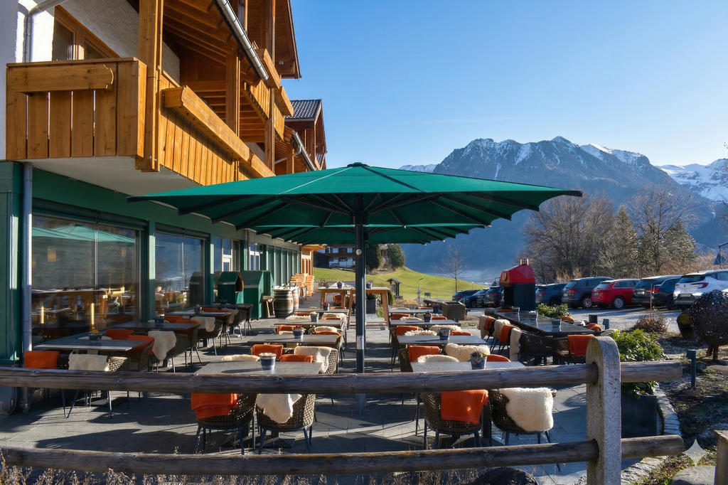 Hôtel avec des Parasols verts et une terrasse ensoleillée dans les montagnes.