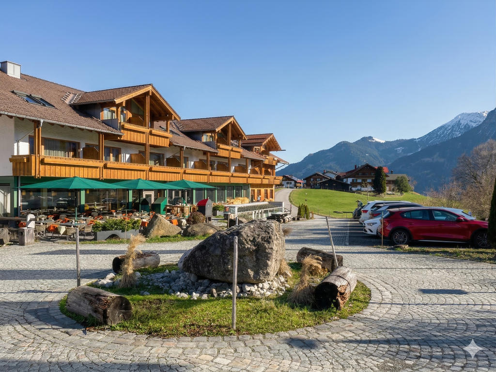 Hôtel avec des Parasols verts et une terrasse ensoleillée dans les montagnes.