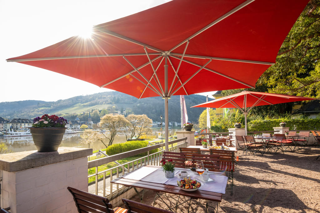 Moselschlösschen mit roten FILIUS Schirmen Rote Sonnenschirme vor einem Wellnesshotel