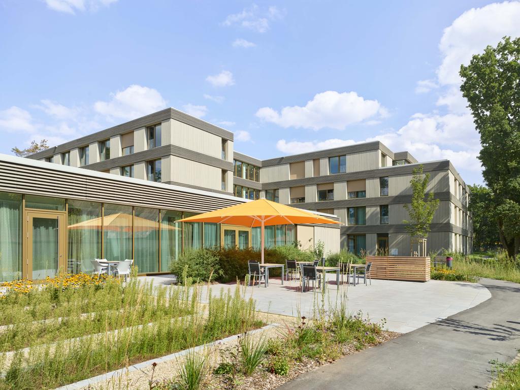 Hotelterrasse mit orangem Sonnenschirm und gemütlichen Sitzplätzen im Außenbereich.