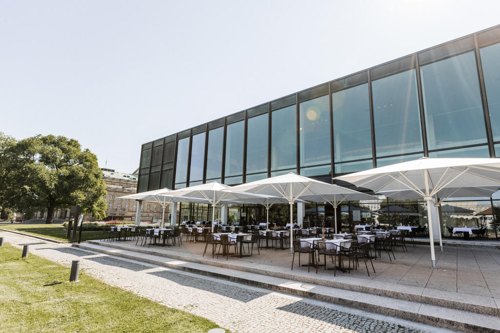 Plenum, Stuttgart with white SCHATTELLO parasols A modern glass building with white parasols lining the terrace in a green setting