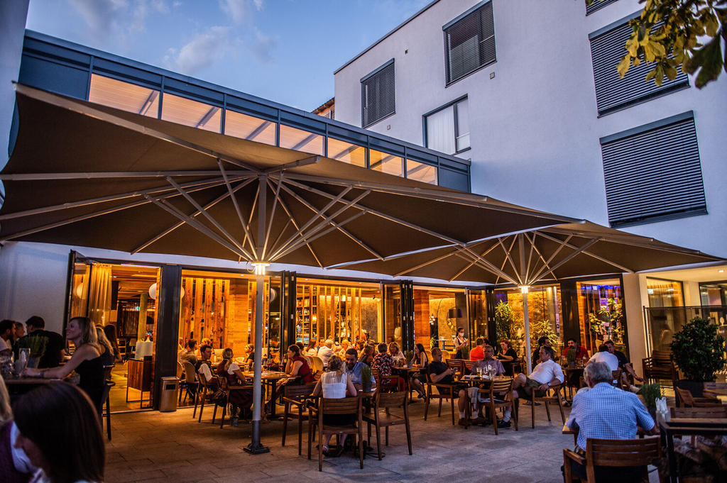 Toni’s Gasthaus mit braunen ALBATROS Schirmen Terasse von einem Gasthaus mit zwei braunen Sonnenschirmen