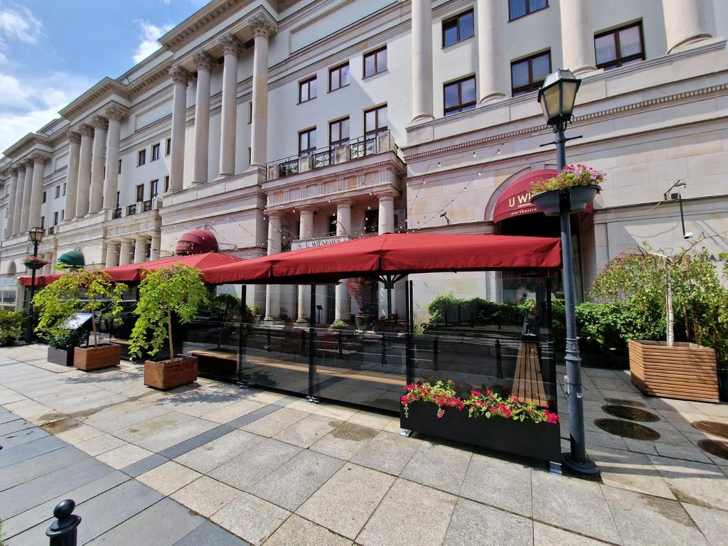 Historisches Gebäude mit Terrasse und roten Sonnenschirmen.