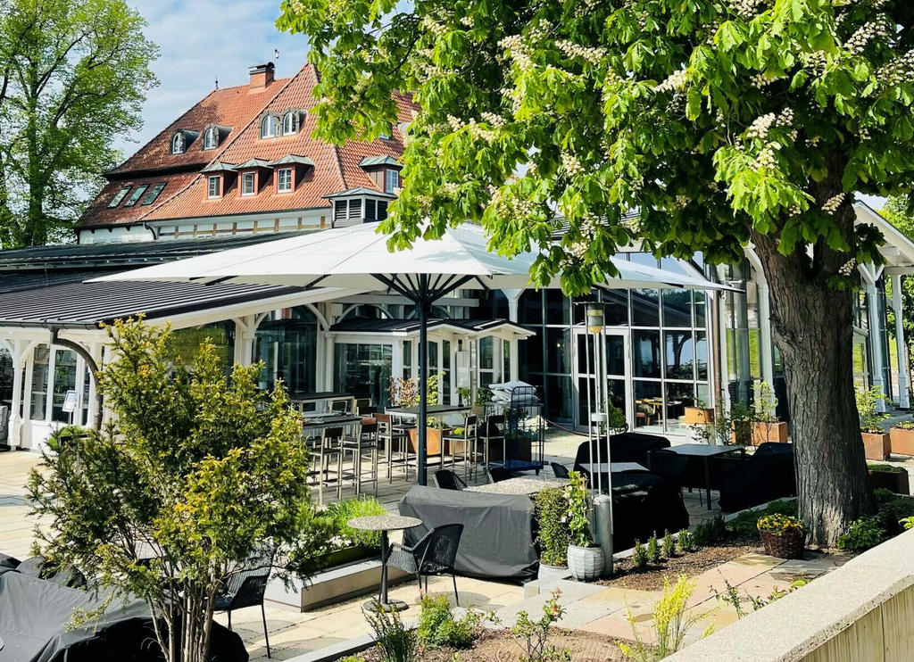 Zollenspieker Fährhaus mit weißen ALBATROS Schirmen Gastronomie-Terrasse an einem See mit Sonnenschirmen