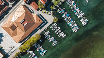 Inselhalle, Lindau avec des parasols gris SCHATTELLO Un port avec une maison en bois et une terrasse avec des parasols gris.